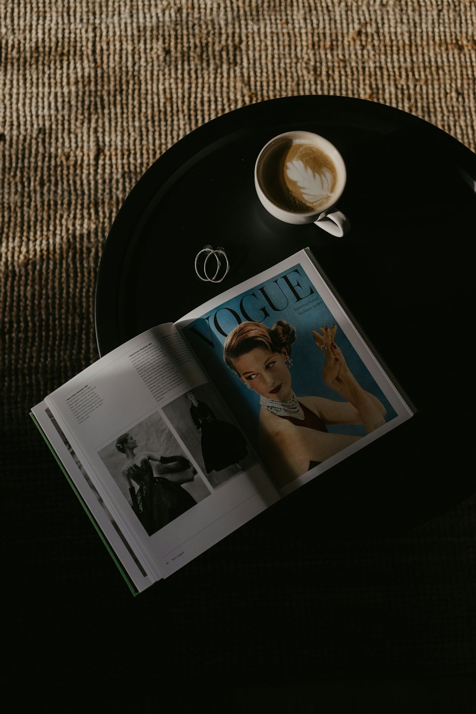 Masanın üzerinde kahve ve küpelerle açık moda dergisi.